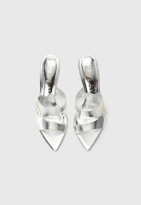 Zilveren metallic hoge hakken met een puntige neus, zijuitsnijding en twee kruisende bandjes over de voet.