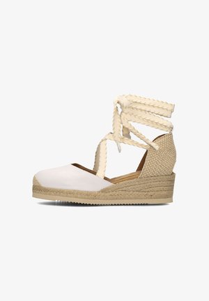 White leather espadrille wedge with braided textured ankle straps and a jute-wrapped midsole, featuring a rounded toe design and beige rubber outsole.