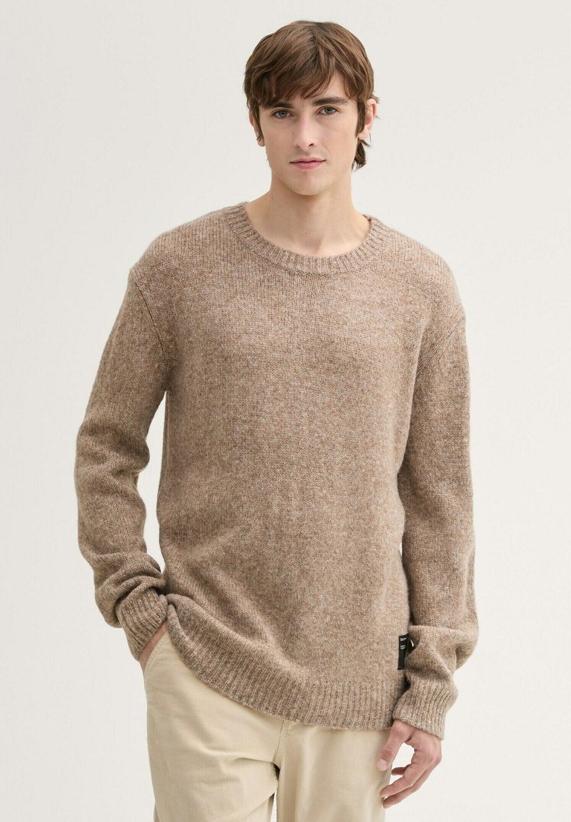 Hellbrauner gestrickter Pullover mit rundem Halsausschnitt, gerippten Bündchen und Saum. Weiche Textur mit lässiger Passform, Detail-Tag an der Seite.