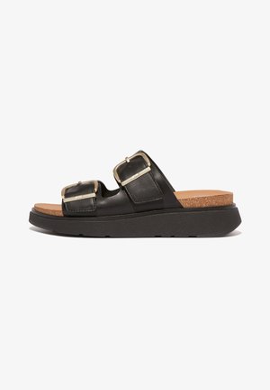 Black leather slide sandals with two adjustable straps, metal buckles, and a cork footbed on a thick black outsole.