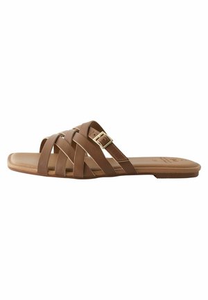 Sandales à semelle plate marron avec des brides croisées, dont une ornée d'une boucle dorée. La semelle est plate et en matériau lisse.
