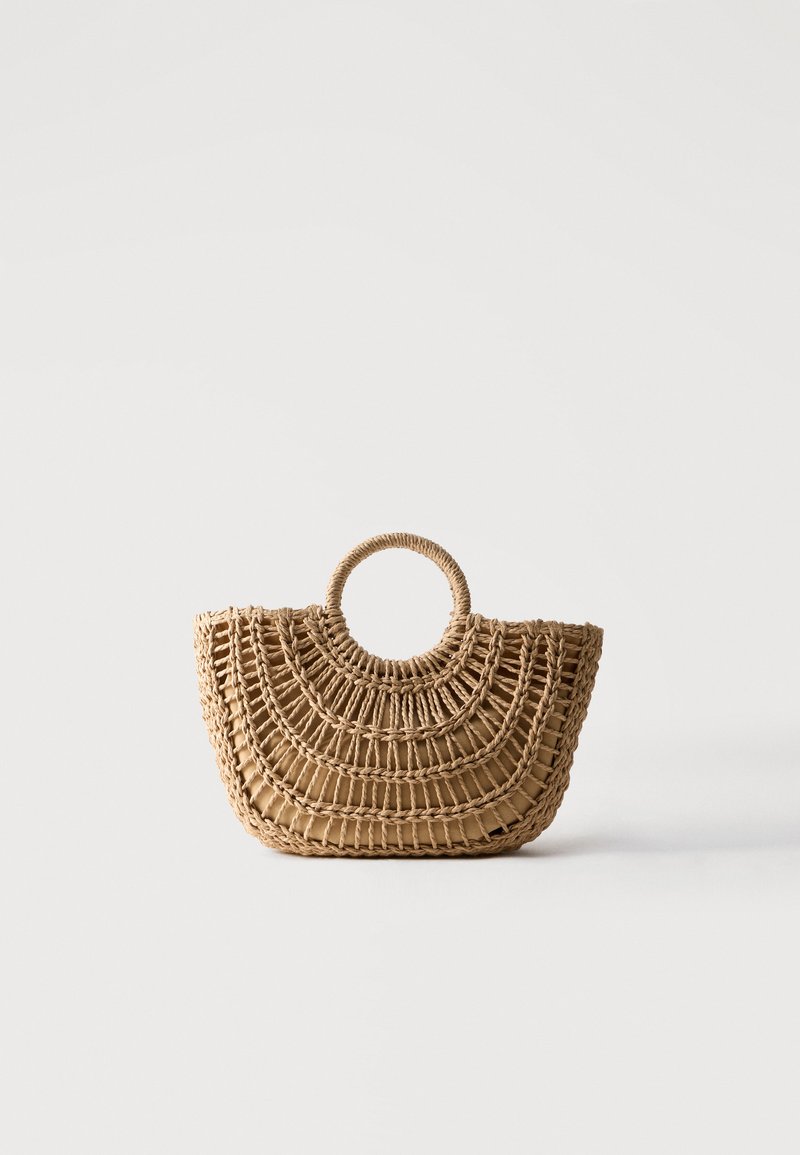 Sac à main en paille tressée avec poignée ronde et motif semi-circulaire, couleur marron clair naturel, sur fond blanc.