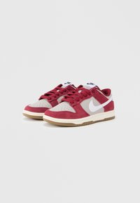 Crvene i sive tenisice od brušene kože i kože, s prozračenim vrhom, bijelim Nike logom i gumenim potplatom s teksturiranim gaznim slojem.