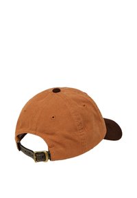 Casquette de baseball en toile marron avec une visière de couleur marron plus foncée, bande en cuir ajustable, bouton rond sur le dessus et trous de ventilation.