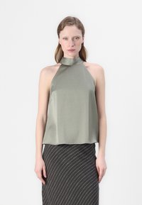 Oliven grønn sateng halter-top med høy hals, glatt tekstur og avslappet passform. Kombinert med et svart og hvitt stripete skjørt.