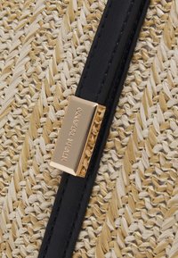 Woven straw bag with a black leather strap, featuring a gold-tone metal clasp with "RIVER ISLAND" engraved, showcasing a textured surface.