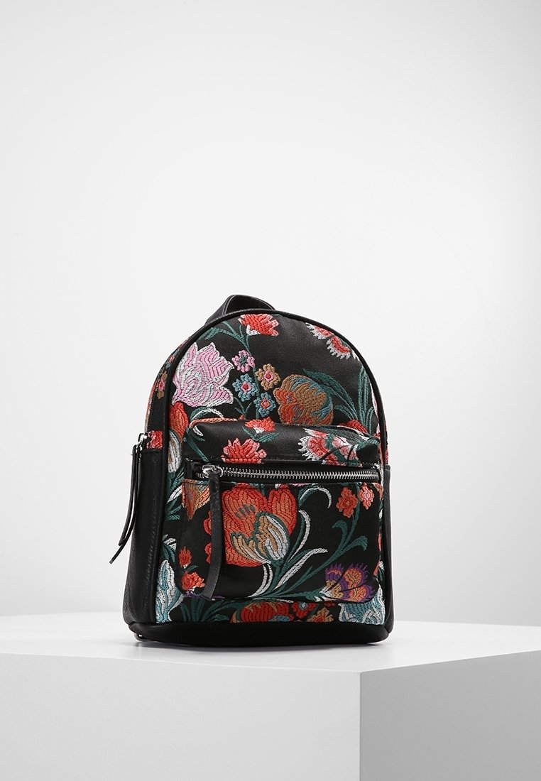 Plecak wykonany z czarnej tkaniny, ozdobiony kolorowym haftem kwiatowym. O zaokrąglonym kształcie, z przednią kieszenią na zamek błyskawiczny i regulowanymi paskami.