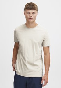 Beige kortærmet T-shirt med rund hals, lavet af et glat bomuldsstof. Har en afslappet pasform og diskret detalje ved sidesømmen.