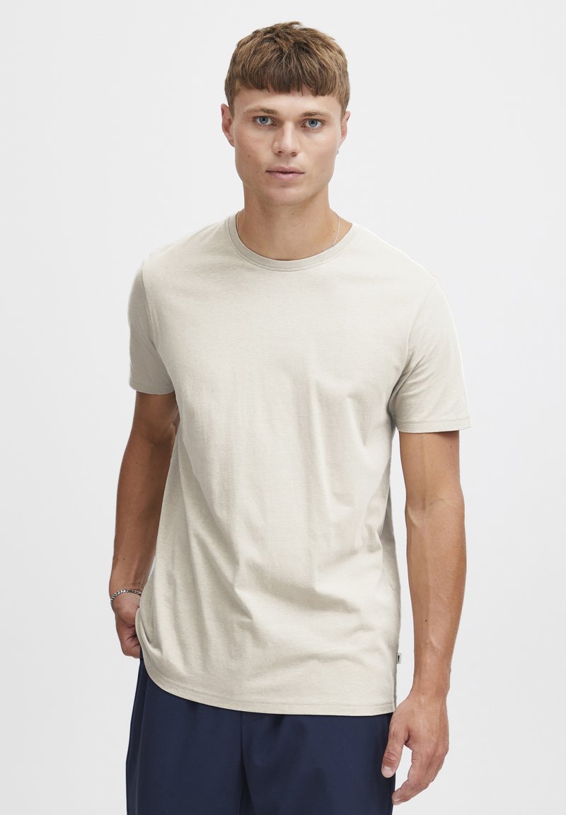 Beige kortærmet T-shirt med rund hals, lavet af et glat bomuldsstof. Har en afslappet pasform og diskret detalje ved sidesømmen.