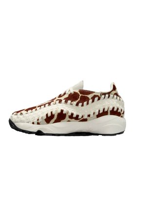 Zapatilla slip-on con un upper de piel de vaca que presenta un patrón marrón y blanco. Acentos tejidos blancos, suela ligera y suela negra texturizada.