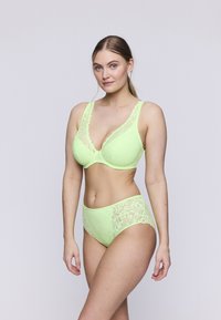Neon gele kant lingerie set met een diep uitgesneden beha met brede bandjes en hooggeplaatste slipjes met bloemenpatronen.