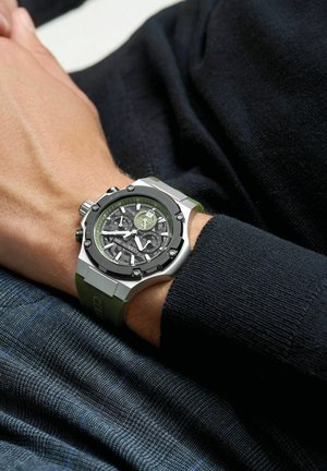 Orologio in acciaio inossidabile silver con dettagli neri e verdi, quadrante grigio texturizzato, funzionalità cronografo e cinturino in silicone verde.