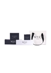 Een verzameling van zwart-witte dozen en een witte tas, allemaal voorzien van de tekst "MYC PARIS" in een elegante lettertype. De tas heeft een zwarte handgreep.