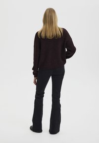 Maroon knit sweater with a relaxed fit, paired with black flared jeans. The fabric appears soft with a slightly fuzzy texture.