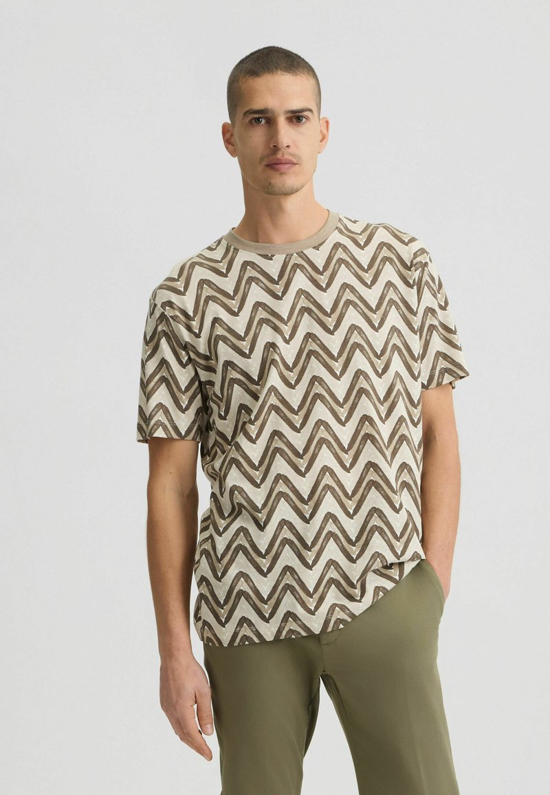 Camiseta de patrón zigzag en marrón y crema, con cuello redondo, mangas cortas y un corte relajado, hecha de una tela ligera.