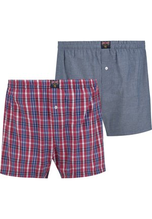 Zwei Paare Herrenboxershorts: eine rot-karierte mit blauen und weißen Akzenten, die andere einfarbig grau. Beide verfügen über elastische Taillenbünde und Frontknöpfe.