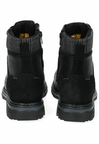 Botas de tobillo de cuero negro con un cuello de tela gris texturizada, cremalleras laterales y suelas gruesas de goma negra. Costuras detalladas en el cuero.