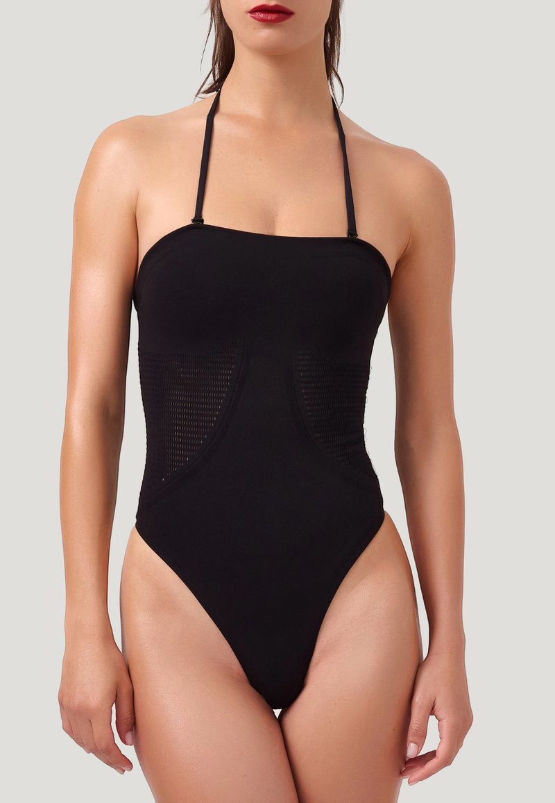Maillot de bain une pièce noir avec cou à nouer, doté de panneaux latéraux en mesh, d'ouvertures de jambes haute et d'une texture lisse et soyeuse.