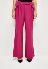 Pantalons larges en tissu fuchsia vif. Dotés d'une taille haute avec un détail en nœud et poches latérales. Texture lisse, coupe ajustée.