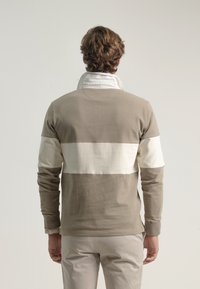Sudadera de cuello redondo en beige y blanco roto. Material de algodón suave, diseño a bloques de color, con mangas largas y cuello de solapa.