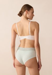 Witte beha met kantafwerking en verstelbare bandjes, gecombineerd met mintgroene en witte gestreepte high-waisted slipjes met een bloemenkant tailleband.