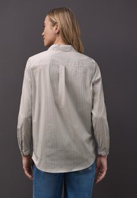 Lekko prążkowana koszula z długim rękawem wykonana z miękkiej tkaniny, z kołnierzykiem, plisą z tyłu i mankietami zapinanymi na guziki.