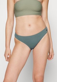 Zeleni rebrasti bandeau top in ujemajoči se bikini spodnji del z teksturirano obdelavo, ki vključuje tanek pas in malo logotipno podrobnost na strani.