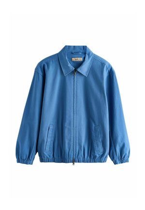 Giacca blu con zip e collo, polsini ed orlo elasticizzati, e due tasche anteriori a fessura su sfondo bianco.