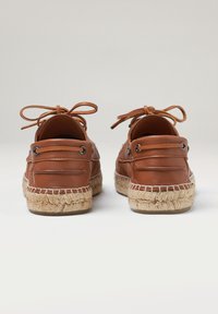 Espadrilles de piel marrón con punta redonda, suela trenzada de yute texturizado, detalle de cordones y ojales de metal negro. Vista posterior mostrada.
