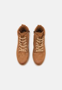 Botas de tobillo de ante marrón claro con una superficie texturizada, que presentan cordones crema, cremalleras laterales y un cuello acolchado para mayor comodidad.