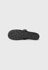 Black sandal sole features an embossed floral pattern, made of rubber with a smooth texture. Includes a side buckle detail for adjustment.