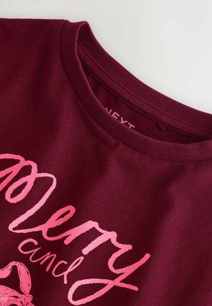 Bordeauxfarbenes T-Shirt mit Rundhalsausschnitt und einem grafischen Design in Pink, das den Text "Merry" und eine Illustration eines Zuckerstängels zeigt.