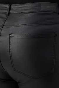 Black faux leather pants featuring a smooth texture, back pockets, and contrasting stitching details. Tag with brand visible at the waistband.