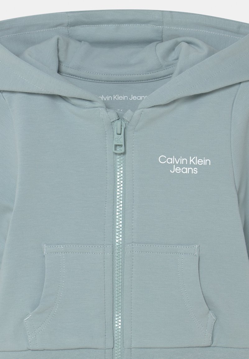 Kinder Jumpsuits & Playsuits | Calvin Klein Jeans STACK LOGO ZIP THROUGH UNISEX SET Trainingsjacke muted aqua/hellblau - KR10012 Kinder Jumpsuits & Playsuits | Calvin Klein Jeans STACK LOGO ZIP THROUGH UNISEX SET Trainingsjacke muted aqua/hellblau - KR10012