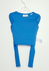 Niebieski długi rękaw crop top wykonany z prążkowanego materiału, z okrągłym dekoltem i metką z boku, zawieszony na przezroczystym plastikowym wieszaku.