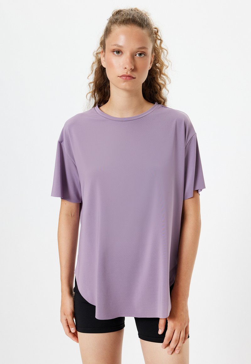 Lilla kortærmet T-shirt med rund hals, løs pasform og glat stof med en let glans, parret med sorte shorts.