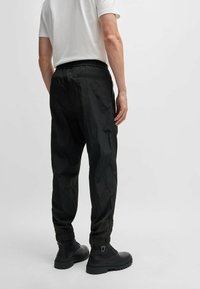 Mustat kevyet housut, joissa on joustava vyötärö, kootut hihansuut ja ryppyinen pinta. Yhdistetty mustiin taistelukenkään.