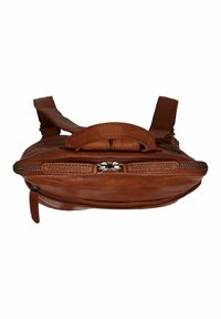 Mochila de cuero marrón con una textura suave, asa superior, correas ajustables y cierre con cremallera que presenta herrajes plateados.