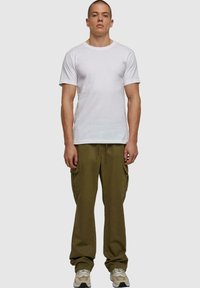 Hvid bomulds t-shirt parret med olivengrønne cargo-bukser, der har sidelommer og en afslappet pasform. Skoene er beige med sorte accenter.