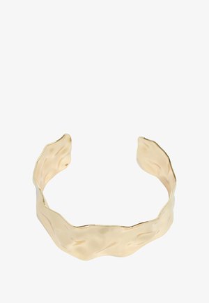 Bracciale a cuffia in metallo dorato lucido con un design ondulato e testurizzato e estremità aperte, caratterizzato da bordi irregolari per un aspetto unico.