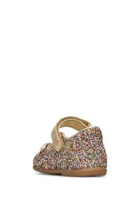Zapato tipo Mary Jane para niña, brilloso y multicolor, con correa dorada y suela de goma, visto desde la parte trasera sobre un fondo blanco.