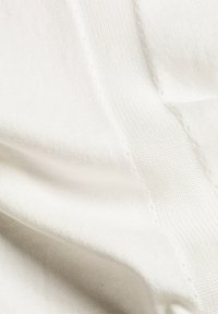 Valkoinen kangas, jossa on sileä pinta ja hienovarainen poikkiraidoitus, joka näyttää pehmeiltä laskoksilta ja kevyeltä ulkonäöltään.