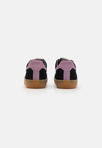 Svarte og rosa semskede joggesko med gummisåle. Har preget "GUESS" merkevaren på hælen og et kontrasterende bakpaneldesign.