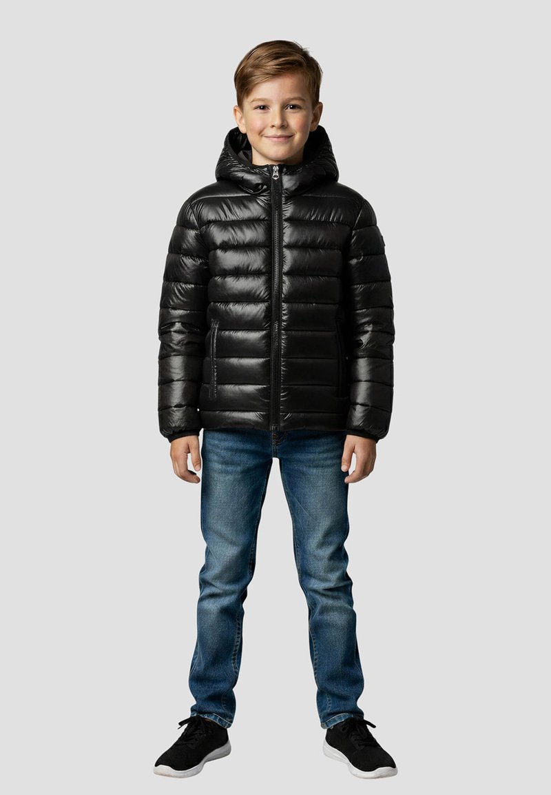 Czarna pikowana kurtka puchowa z kapturem, zapinana na zamek z przodu, z przeszyciami oraz bocznymi kieszeniami, noszona na niebieskich dżinsach i czarnych trampkach.