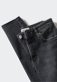 Jean en denim gris foncé plié à plat avec poche avant visible, bouton, fermeture éclair, passants de ceinture et une étiquette de taille blanche à l'intérieur de la ceinture.