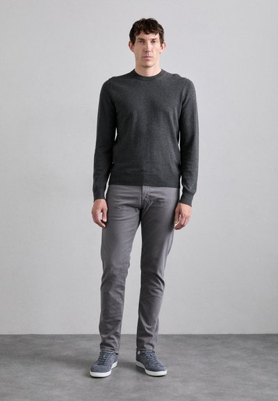 Suéter gris de cuello redondo, combinado con pantalones gris claro y zapatillas gris. La tela parece suave y ajustada, con mangas largas.