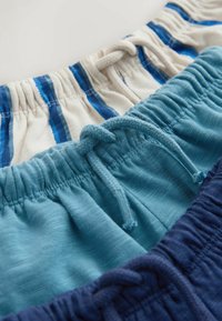 Drie korte broeken: bovenste in off-white met blauwe strepen, middelste in effen lichtblauw, en onderste in donkerblauw. Elastische taillebanden met trekkoorden.