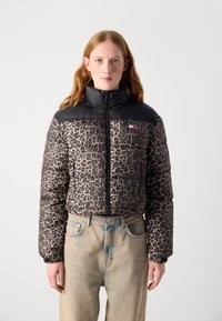 Polstret jakke med leopardmønster og svarte nylon skuldre. Har høy krage og glidelås foran.
