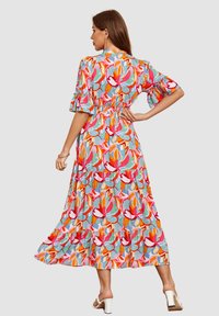 Vestido maxi de patrón floral con mangas con volantes, cintura ceñida y falda fluida; presenta colores vibrantes que incluyen rojo, rosa y azul.