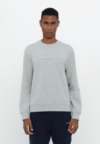 Sudadera gris con cuello redondo, que presenta un logotipo en relieve "MICHAEL KORS" en la parte frontal. Fabricada con un tejido suave y con puños y dobladillo de canalé.